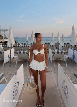 Girl on beach wearing a swim skirt and balconette bikini top in white and navy